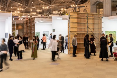 View of an art fair with people walking through the booths.