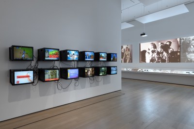 A gallery hung with rows of monitors and filled with projections.
