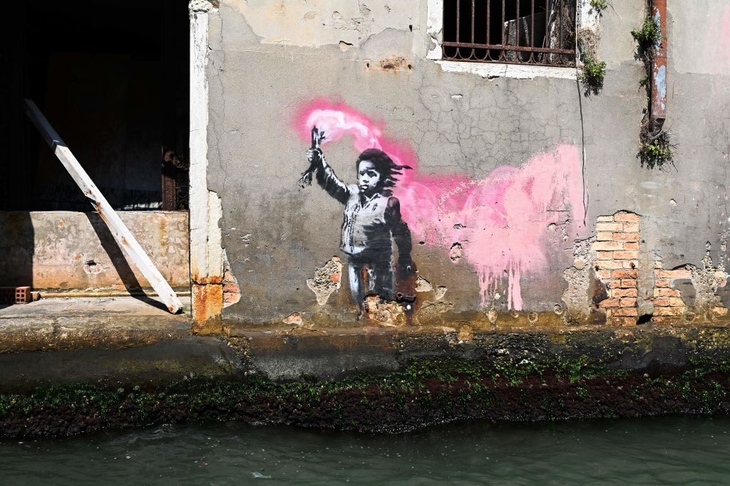 A mural by British street artist Banksy, of a child holding a pink flare, is pictured on August 27, 2019 on a building in Venice. (Photo by Vincenzo PINTO / AFP) / RESTRICTED TO EDITORIAL USE - MANDATORY MENTION OF THE ARTIST UPON PUBLICATION - TO ILLUSTRATE THE EVENT AS SPECIFIED IN THE CAPTION        (Photo credit should read VINCENZO PINTO/AFP via Getty Images)