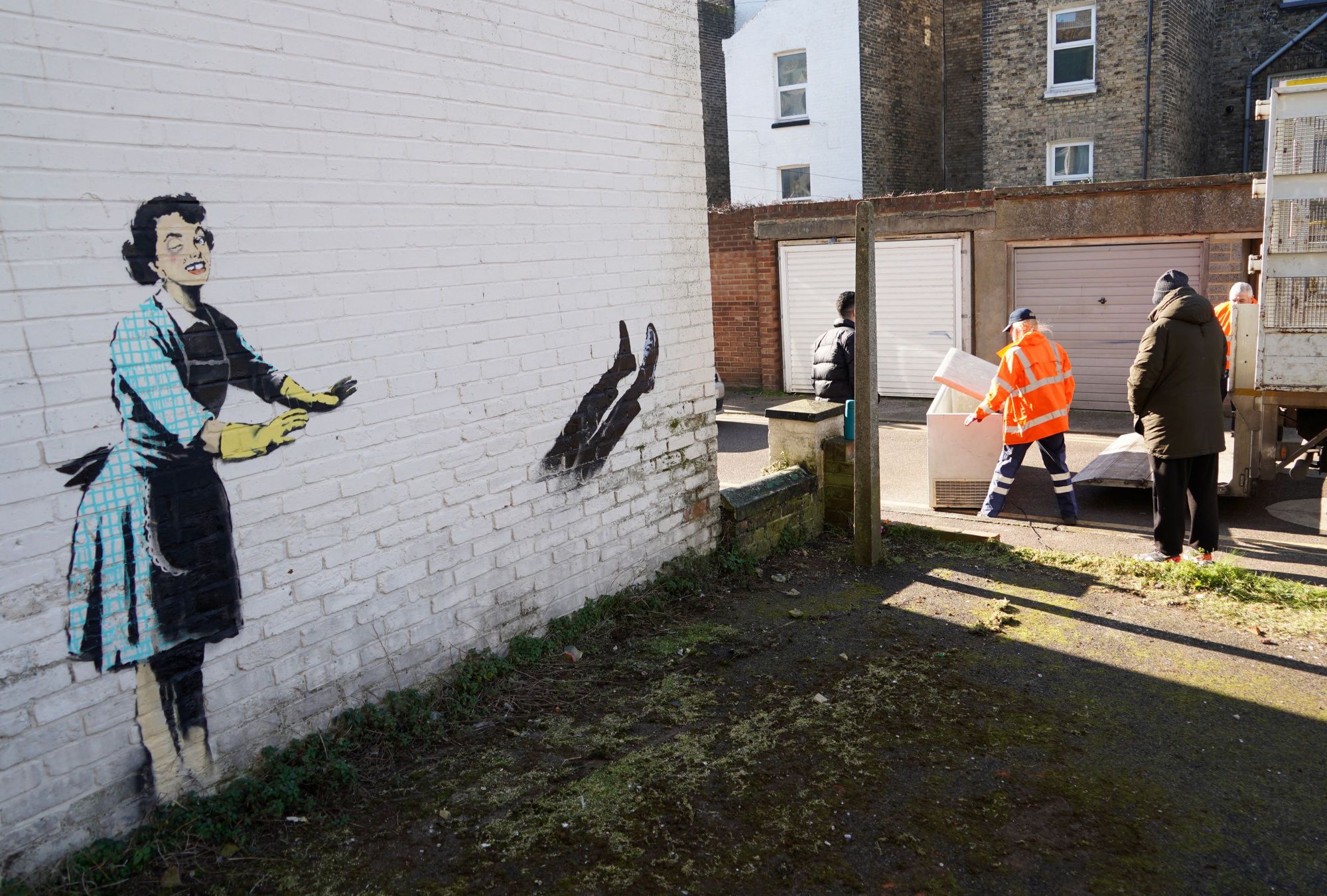 Workers remove a chest freezer that had formed part of an artwork, acknowledged as the work of street artist Banksy, from the side of a house in Margate, in southeast England on February 14, 2023. - The artwork appears to show a 1950s housewife with a swollen eye, missing a tooth, and apparently shutting a man in a freezer. The freezer was later removed by council workers. - RESTRICTED TO EDITORIAL USE - MANDATORY MENTION OF THE ARTIST UPON PUBLICATION - TO ILLUSTRATE THE EVENT AS SPECIFIED IN THE CAPTION (Photo by William EDWARDS / AFP) / RESTRICTED TO EDITORIAL USE - MANDATORY MENTION OF THE ARTIST UPON PUBLICATION - TO ILLUSTRATE THE EVENT AS SPECIFIED IN THE CAPTION / RESTRICTED TO EDITORIAL USE - MANDATORY MENTION OF THE ARTIST UPON PUBLICATION - TO ILLUSTRATE THE EVENT AS SPECIFIED IN THE CAPTION (Photo WILLIAM EDWARDS/AFP via Getty Images)