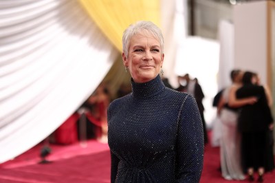 Portrait of Jamie Lee Curtis standing on a red carpet.