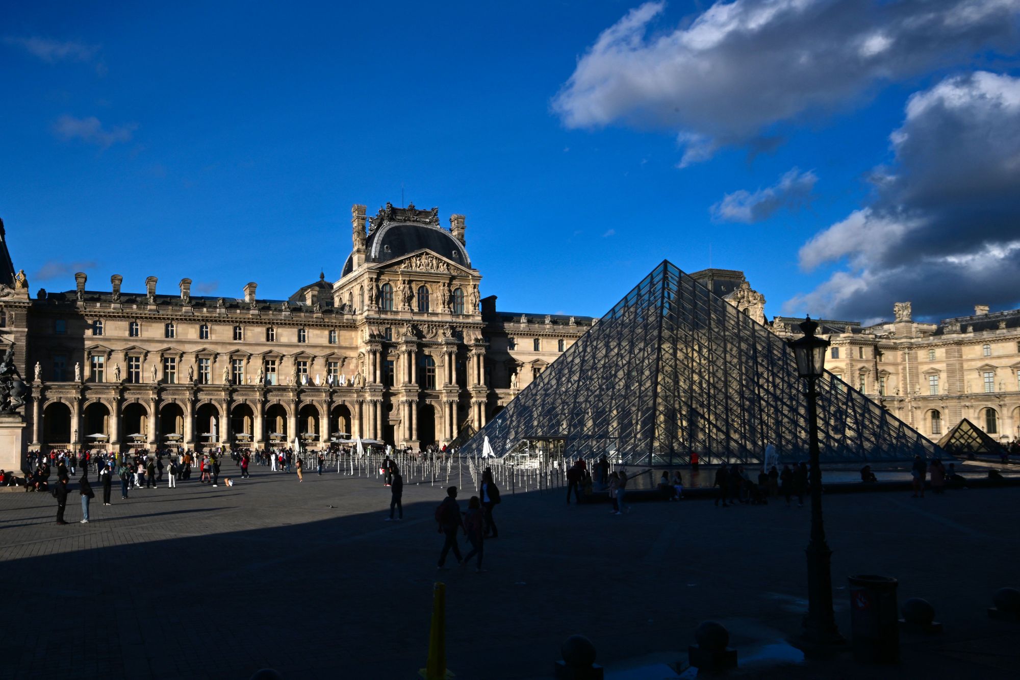 Tourists walk past the Louvre Pyramid, designed by Chinese architect Ieoh Ming Pei at the Louvre museum in central Paris on September 21, 2023. (Photo by MIGUEL MEDINA / AFP) / RESTRICTED TO EDITORIAL USE - MANDATORY MENTION OF THE ARTIST UPON PUBLICATION - TO ILLUSTRATE THE EVENT AS SPECIFIED IN THE CAPTION (Photo by MIGUEL MEDINA/AFP via Getty Images)