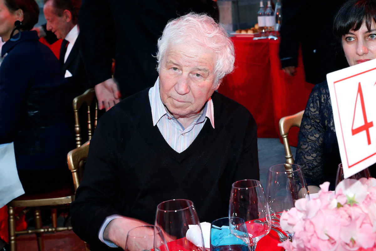 A white man seated at a table lined with wine glasses.