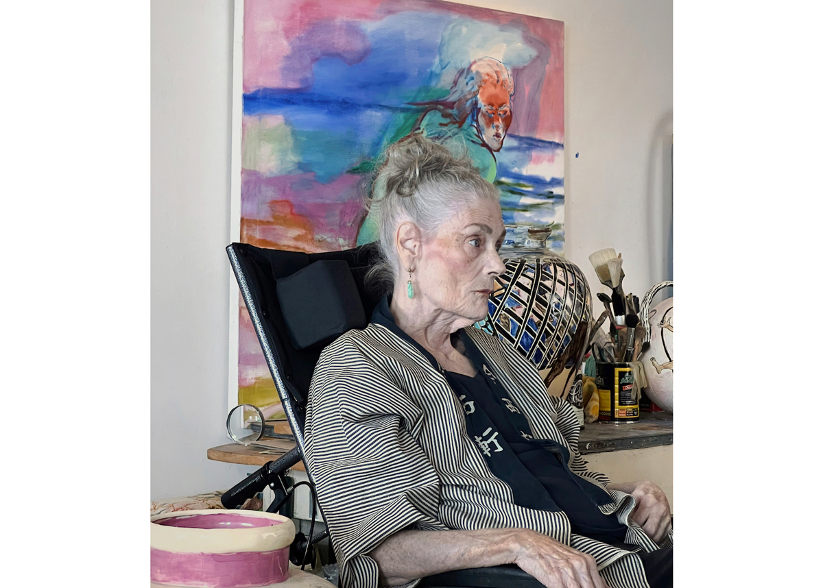 Portrait of Juanita McNeely, seated in front of a painting.