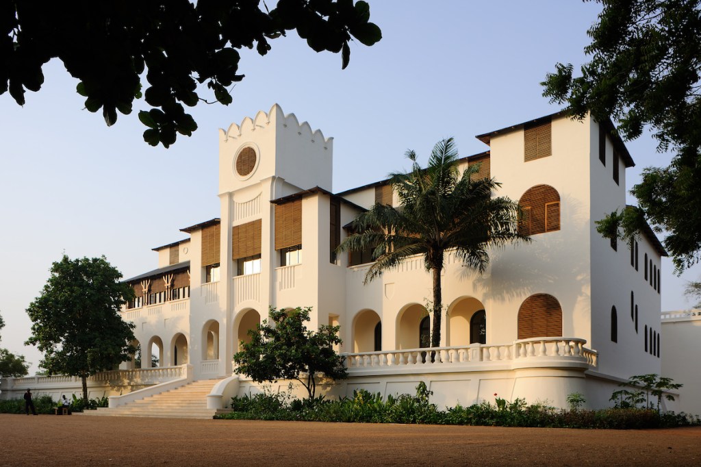 A white building with palm trees on its balconies.