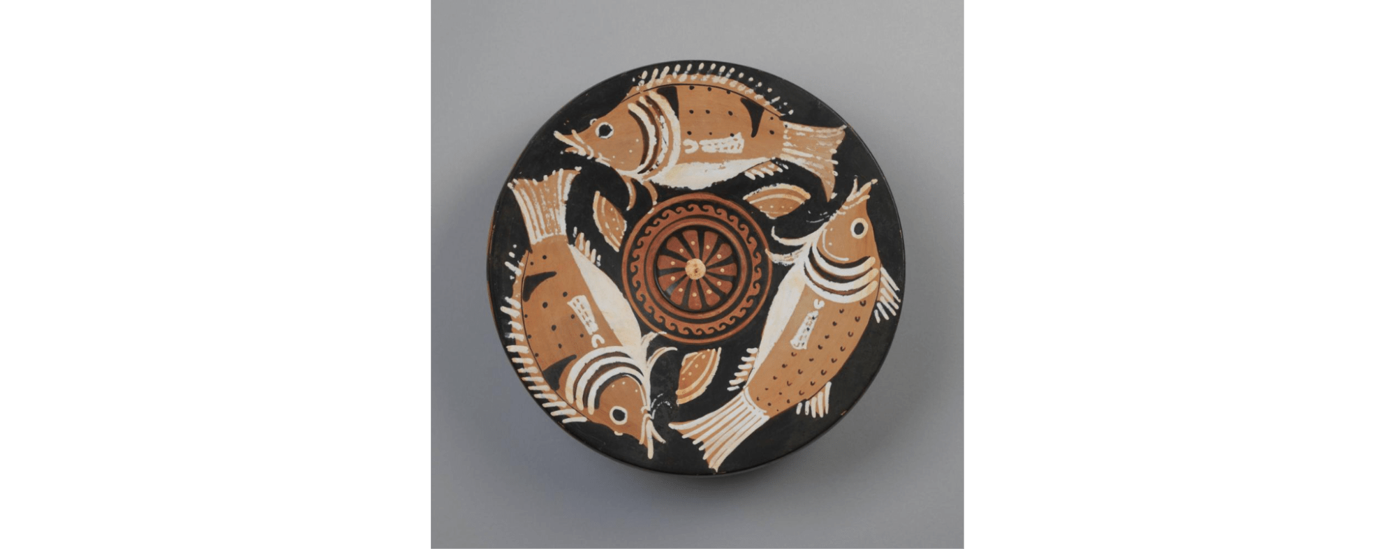A plate decorated with three fish around a central rosette with wave patter.